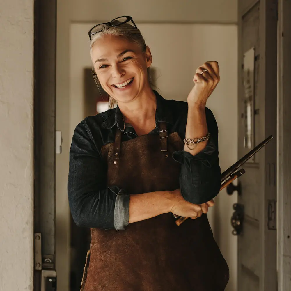Female artist smiling with brushes in hand, showing how independent retirement financial advice supports creative freedom and security.
