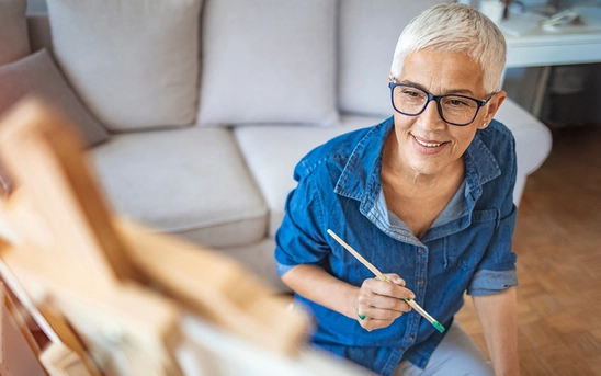 Retired woman painting at home and enjoying creative pursuits