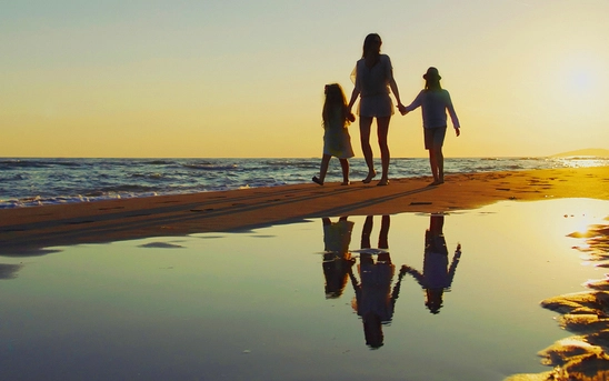 Family walking along the beach at sunset, representing life, family and future planning
